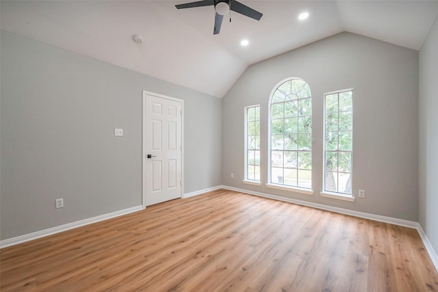 spare room with vaulted ceiling, baseboards, light wood-style flooring, and a healthy amount of sunlight