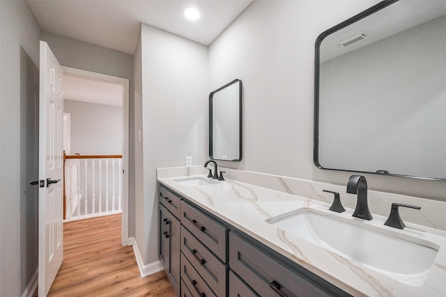 full bathroom featuring double vanity, visible vents, a sink, and wood finished floors