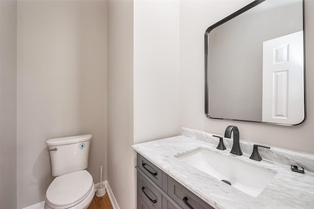 bathroom featuring toilet, vanity, and baseboards