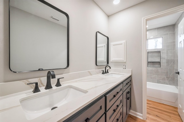 bathroom with double vanity, wood finished floors, a sink, and visible vents