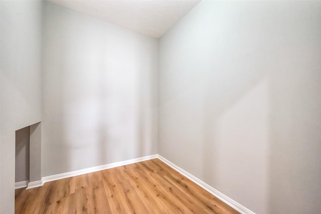 unfurnished room with light wood-style floors, baseboards, and a textured ceiling