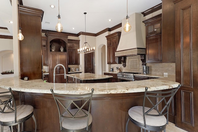 kitchen with arched walkways, custom exhaust hood, tasteful backsplash, dark brown cabinetry, and high end stove