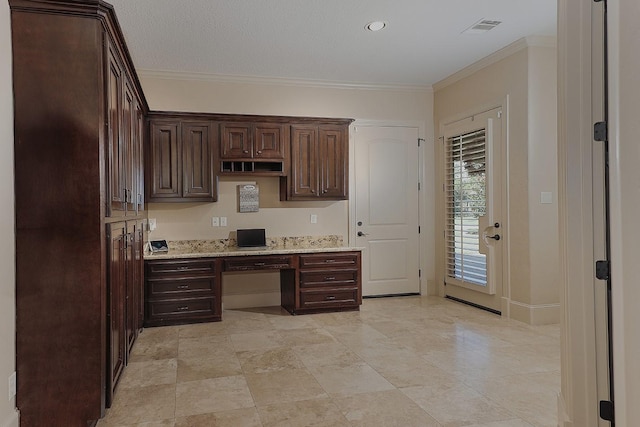 kitchen with dark brown cabinets, ornamental molding, built in study area, and visible vents