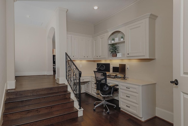 office with baseboards, arched walkways, dark wood finished floors, built in study area, and crown molding