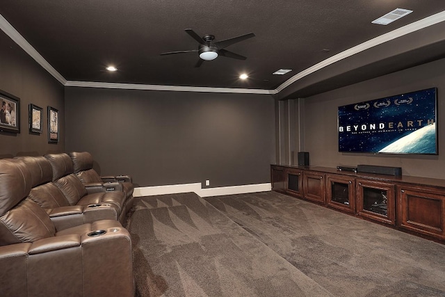 cinema with a ceiling fan, visible vents, baseboards, ornamental molding, and dark carpet