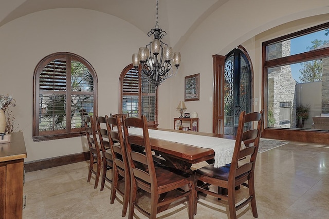 dining room with lofted ceiling, baseboards, arched walkways, and a chandelier