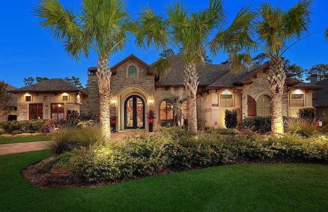 view of front facade with stone siding, a front yard, and stucco siding