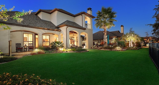 view of front of property with stucco siding, a chimney, fence, and a front yard