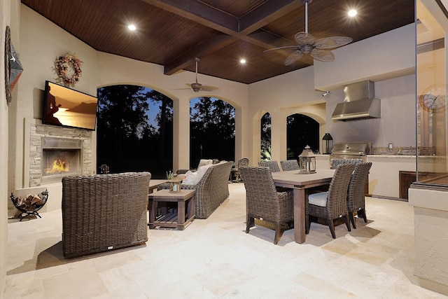 view of patio / terrace with an outdoor living space with a fireplace, a ceiling fan, exterior kitchen, grilling area, and outdoor dining space