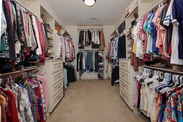 walk in closet with visible vents and light colored carpet