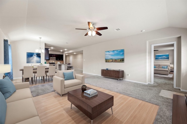 living room with ceiling fan, light colored carpet, visible vents, baseboards, and vaulted ceiling