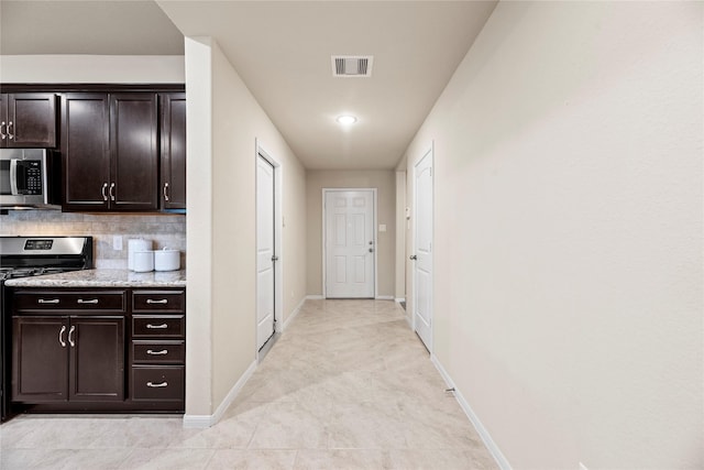 kitchen with baseboards, visible vents, stainless steel appliances, dark brown cabinets, and backsplash