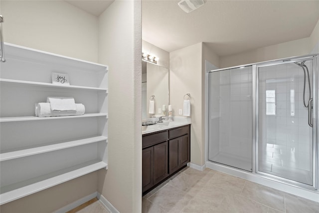 bathroom with tile patterned flooring, vanity, visible vents, baseboards, and a stall shower