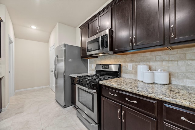 kitchen featuring dark brown cabinetry, baseboards, decorative backsplash, appliances with stainless steel finishes, and light stone countertops