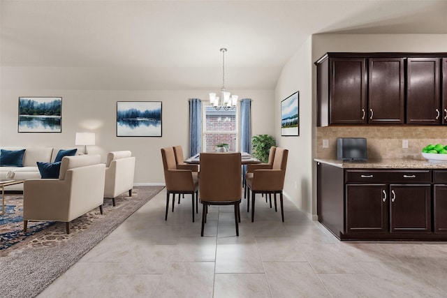 dining space with lofted ceiling, light tile patterned floors, baseboards, and a notable chandelier