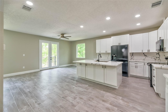 kitchen featuring decorative backsplash, visible vents, a sink, and black appliances