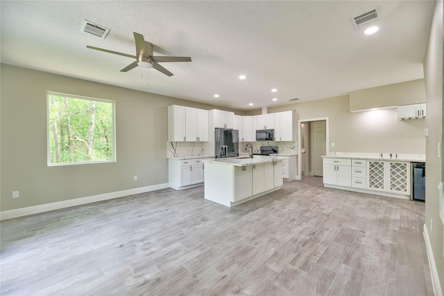 kitchen featuring open floor plan, black appliances, light countertops, and visible vents