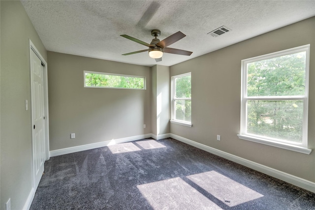 carpeted spare room featuring visible vents, a textured ceiling, and baseboards