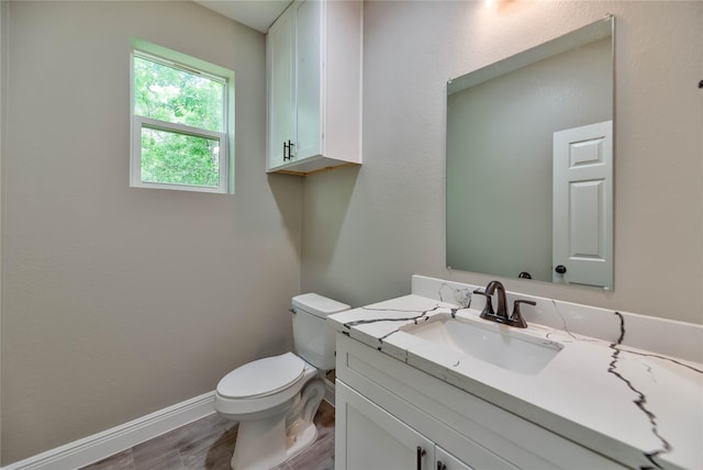 half bath with wood finished floors, vanity, toilet, and baseboards