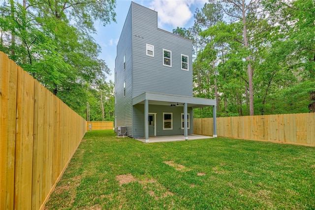 back of property with central AC unit, a lawn, ceiling fan, a fenced backyard, and a patio area