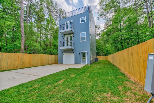 exterior space with an attached garage, a balcony, fence, driveway, and a yard