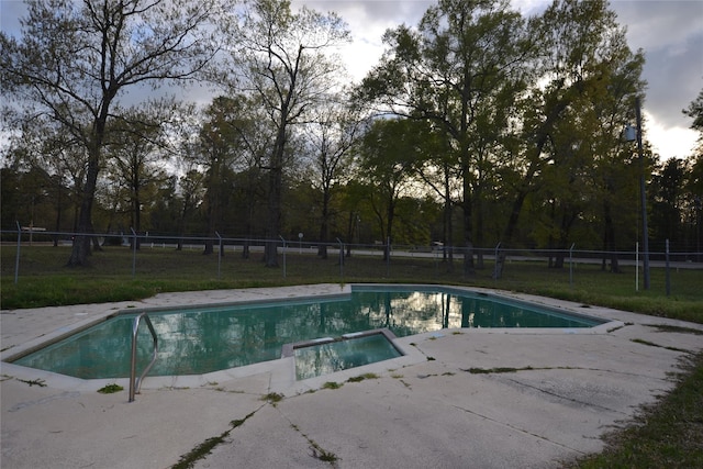 view of pool featuring a lawn, a patio area, fence, and a pool with connected hot tub