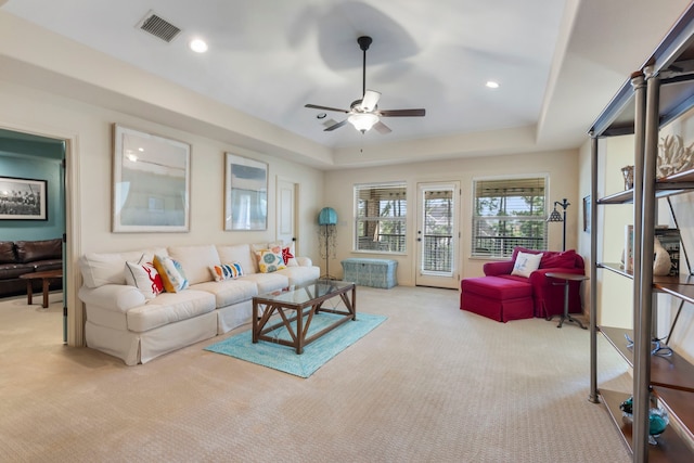 living area with carpet floors, a tray ceiling, visible vents, and recessed lighting