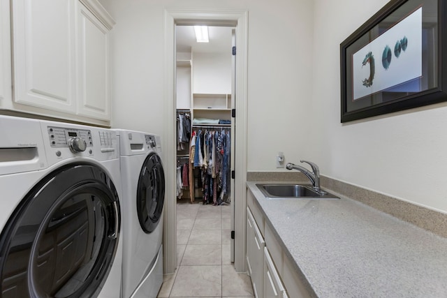 washroom featuring cabinet space, a sink, washing machine and clothes dryer, and light tile patterned flooring