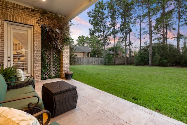 patio terrace at dusk with fence, an outdoor hangout area, and a yard