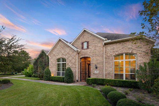 traditional home with a shingled roof, a front lawn, and brick siding