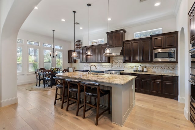 kitchen with arched walkways, appliances with stainless steel finishes, backsplash, and a sink