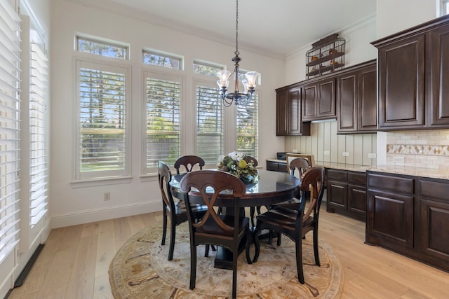 dining space with baseboards, a notable chandelier, light wood-style flooring, and crown molding