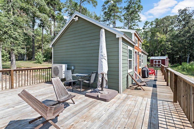 wooden deck featuring a storage shed, ac unit, and an outdoor structure