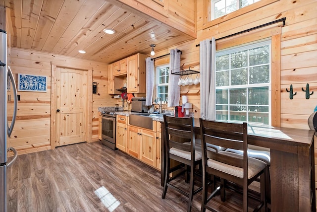 kitchen featuring dark wood finished floors, appliances with stainless steel finishes, wood ceiling, light brown cabinets, and wood walls