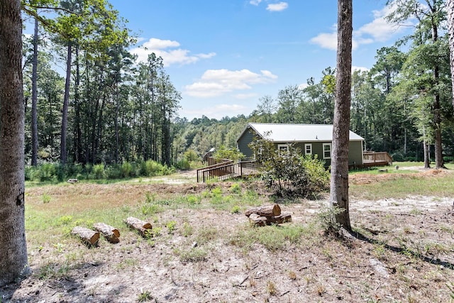 view of yard featuring a forest view and a wooden deck