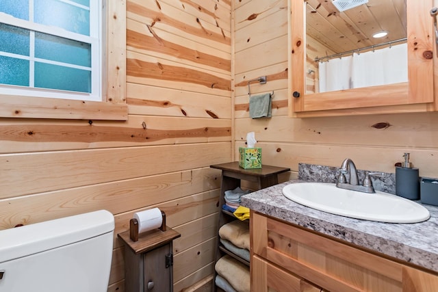 bathroom featuring wooden walls, visible vents, toilet, a shower with curtain, and vanity