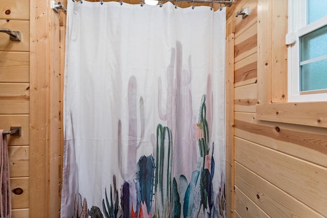 bathroom with a shower with curtain and wooden walls