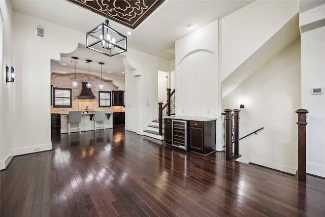 living room with baseboards, visible vents, dark wood finished floors, wine cooler, and an inviting chandelier