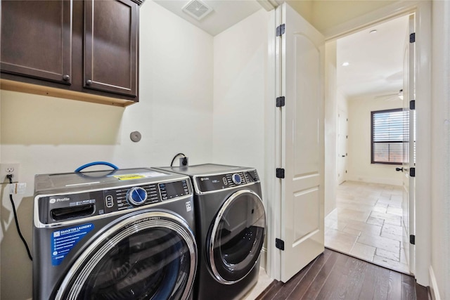 laundry area with cabinet space, baseboards, visible vents, dark wood finished floors, and washer and dryer