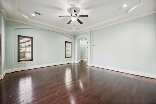 empty room featuring hardwood / wood-style floors, visible vents, a raised ceiling, and arched walkways