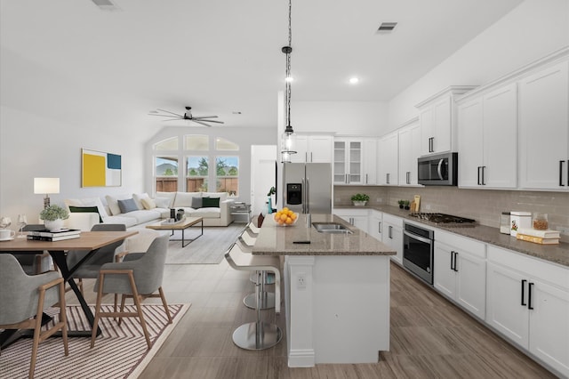 kitchen featuring visible vents, stainless steel appliances, white cabinets, and decorative backsplash