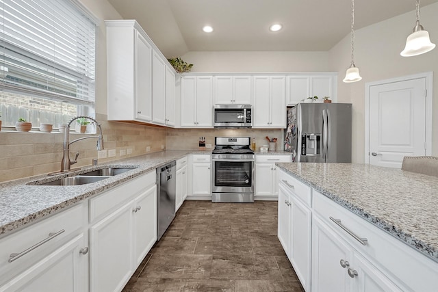 kitchen featuring stainless steel appliances, a sink, white cabinets, and decorative backsplash