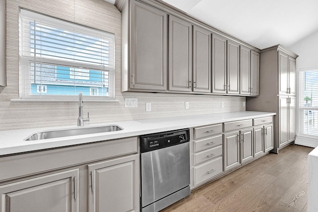 kitchen with gray cabinetry, a sink, light countertops, stainless steel dishwasher, and light wood-type flooring