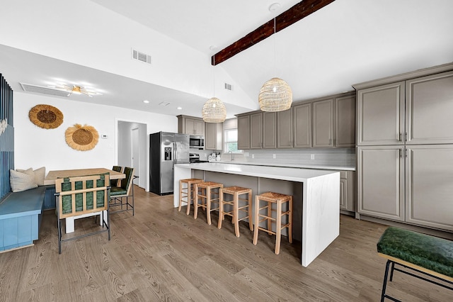 kitchen featuring stainless steel appliances, a breakfast bar area, light wood-type flooring, and gray cabinets