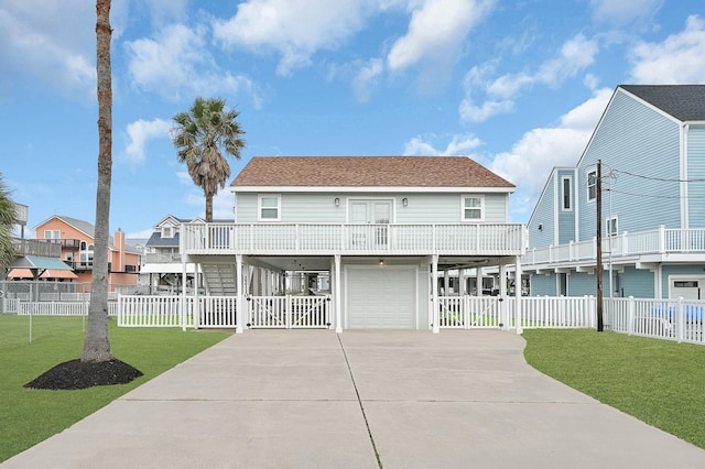 coastal inspired home featuring a shingled roof, fence, a carport, driveway, and a front lawn