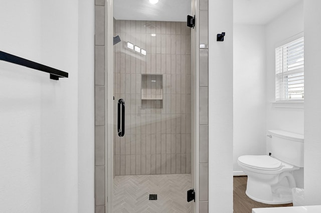 bathroom featuring toilet, a stall shower, and wood finished floors