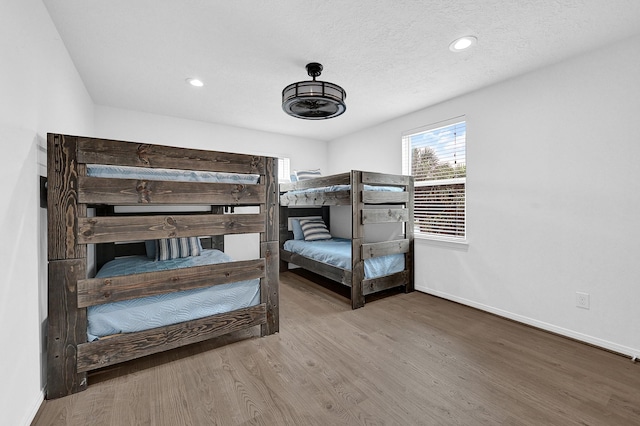 bedroom with recessed lighting, a textured ceiling, baseboards, and wood finished floors