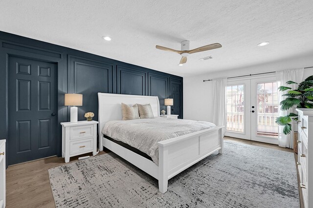 bedroom featuring french doors, visible vents, a decorative wall, light wood-style floors, and access to outside