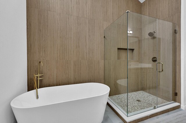 bathroom with a freestanding bath, a stall shower, and tile walls