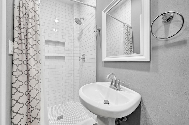 bathroom featuring a shower stall, a sink, and a textured wall